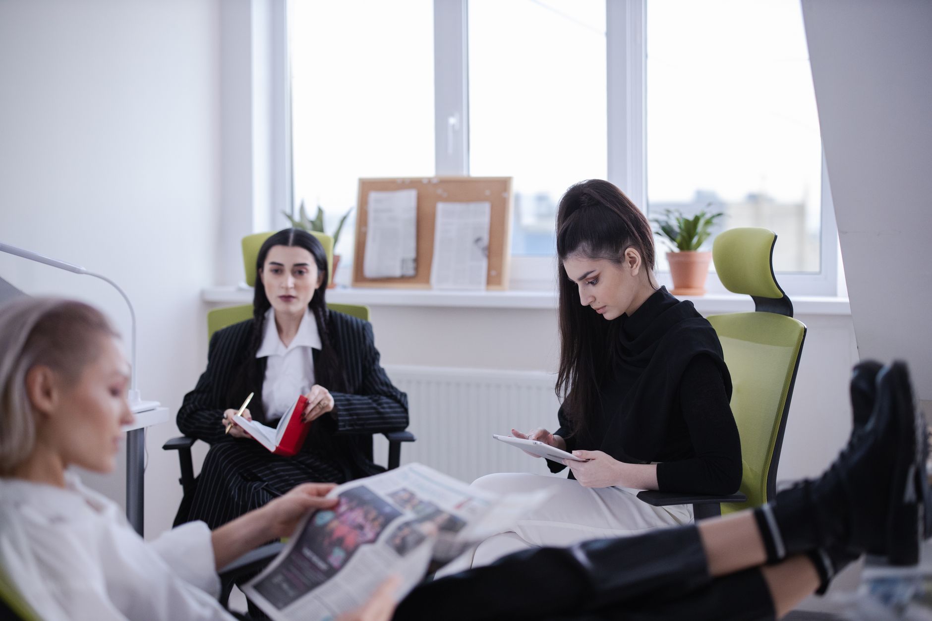 Three women in a modern office setting reading and working together indoors. — Selecting the right Virtual Data Room