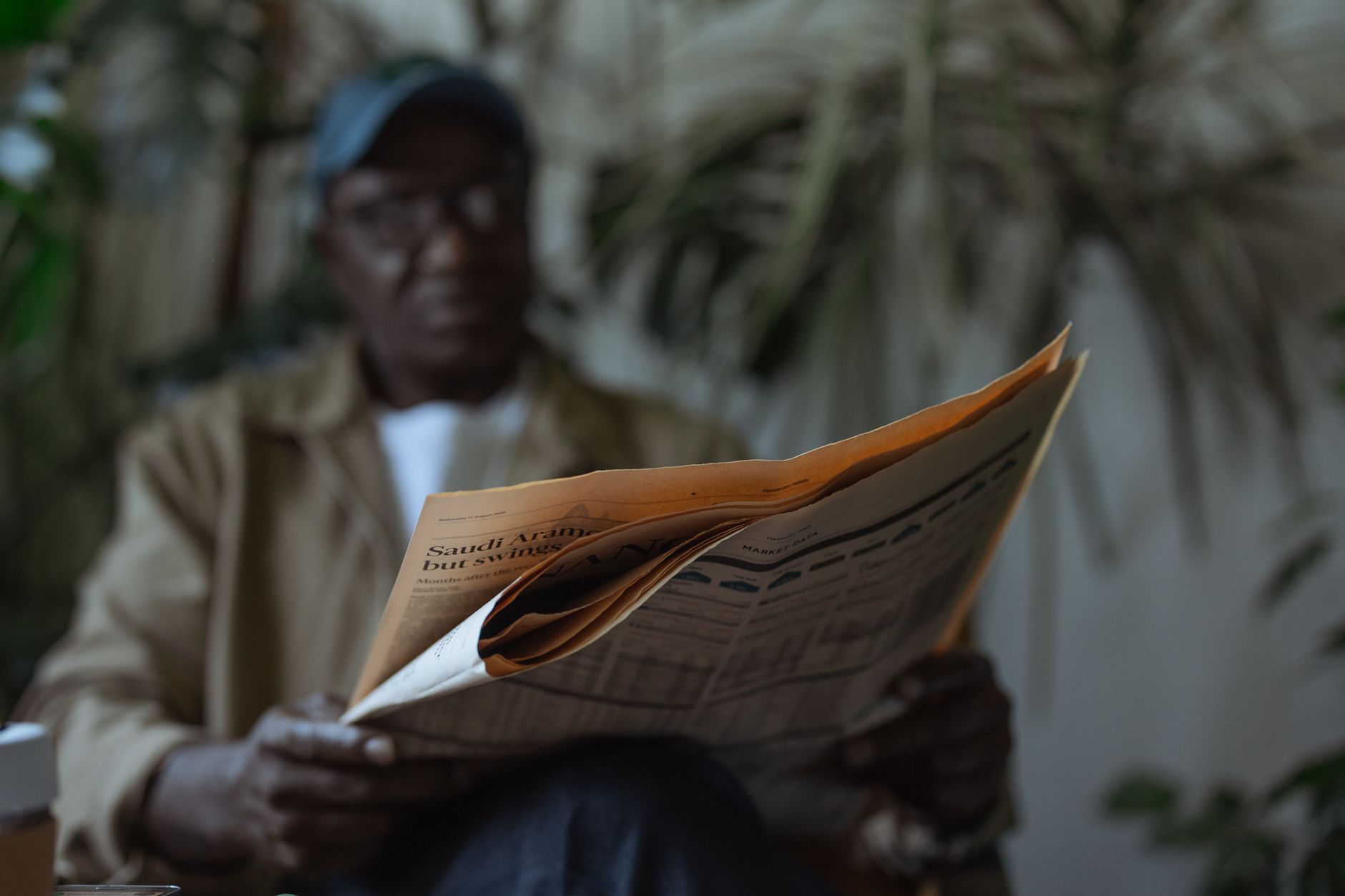 An adult man reading a newspaper indoors, surrounded by plants with a blurred background. — The right way to Hold a Successfu
